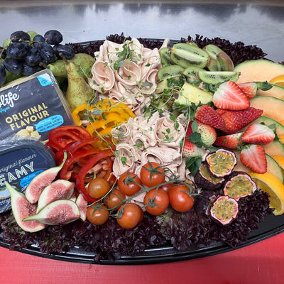 Platå med färska fikon, tunna skivor av skinka och en mix av olika frukter.
