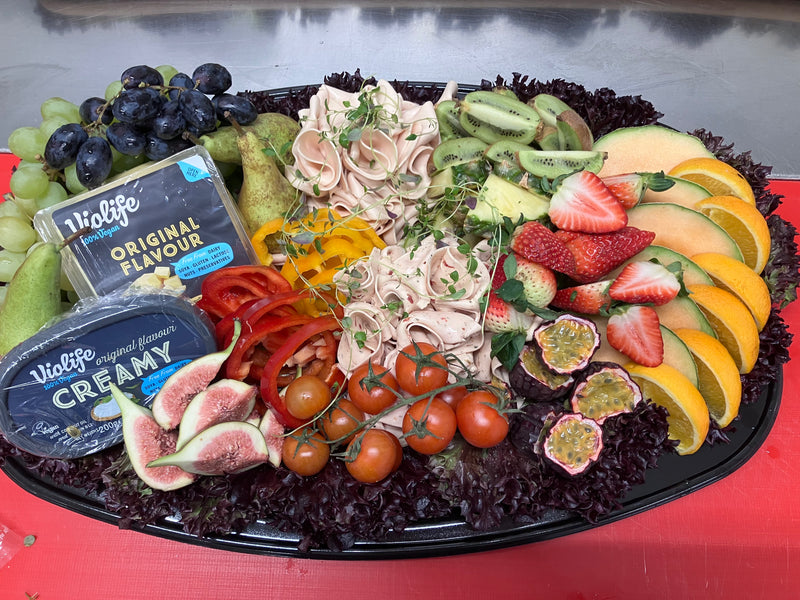 Platå med färska fikon, tunna skivor av skinka och en mix av olika frukter.