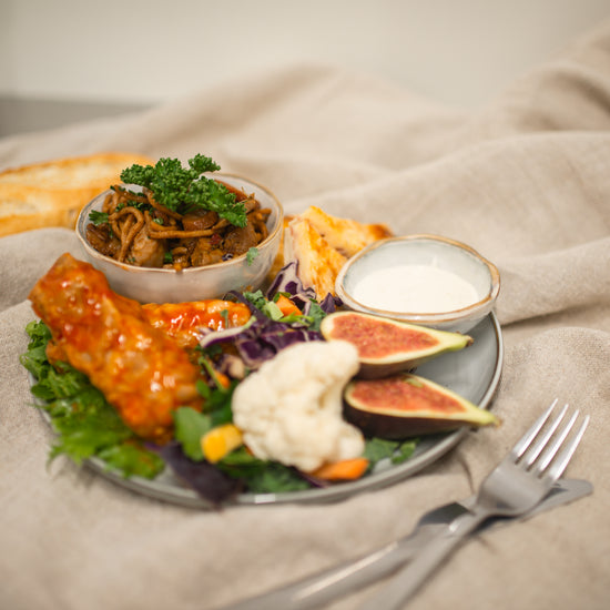 En lockade tallrik med olika proteinkällor, fikon, blomkål och en passande sås