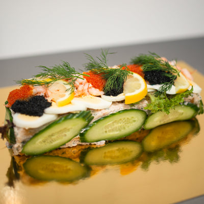 En lockande smörgåstårta med skikt av smakfulla pålägg, dekorerad med kaviar, ägg och grönsaker