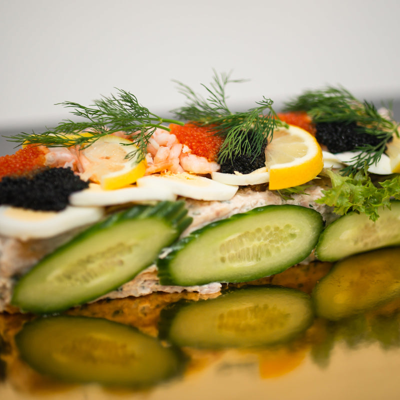 En vacker smörgåstårta med dekorativa mönster av pålägg och grönsaker. 