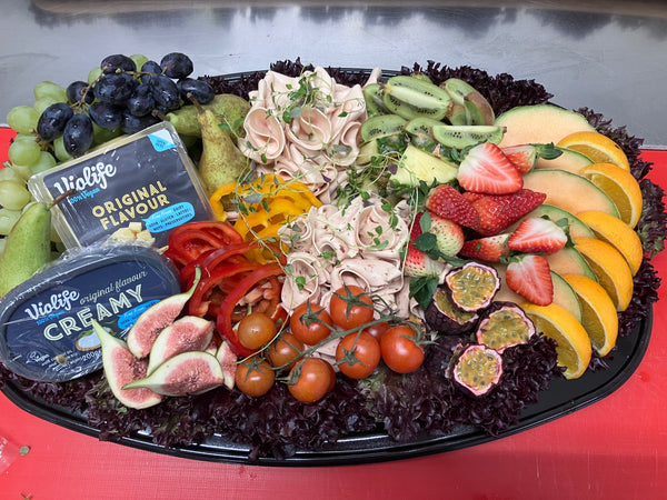 Platå med färska fikon, tunna skivor av skinka och en mix av olika frukter.